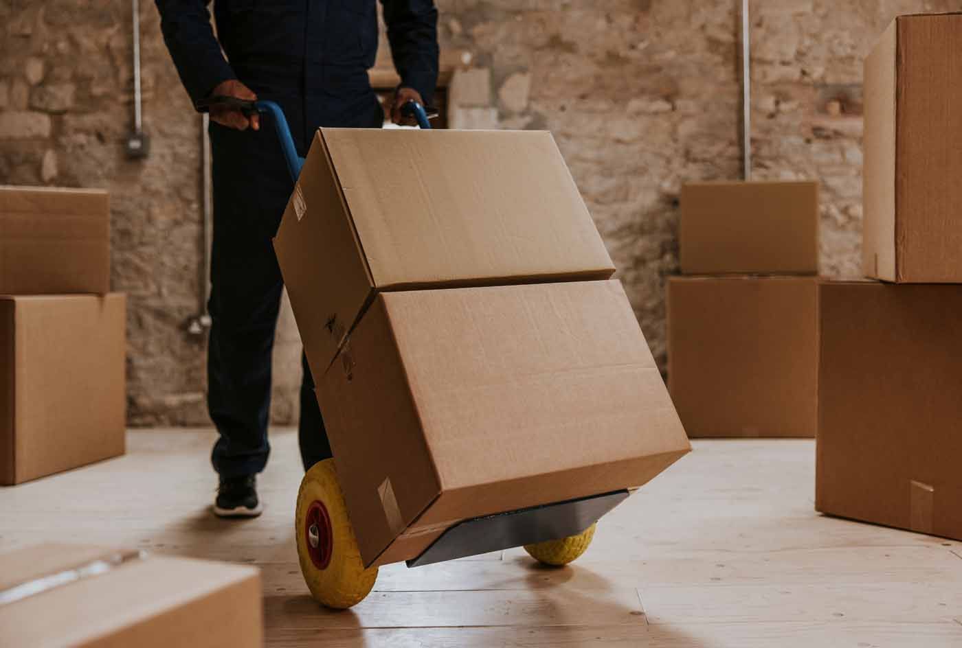 A man is pushing a cart with boxes on it in a warehouse.