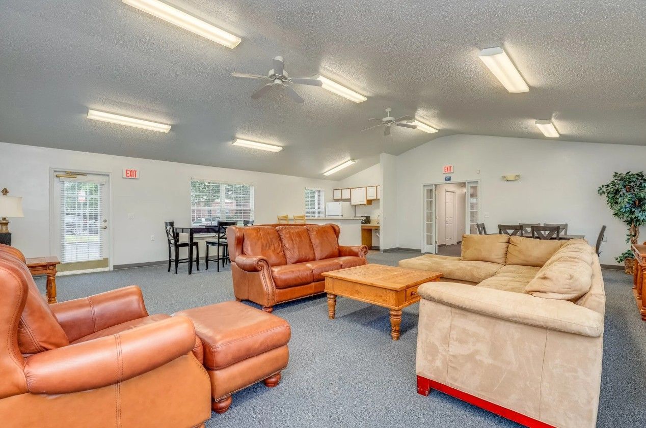 A spacious living area with two leather sofas, a tan fabric sofa, a wooden coffee table, and a small dining set.