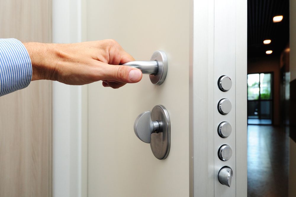Hand Opening a Light-colored Door With Silver Handle and Security Bolts — Yamba Locksmiths in Clarence Valley, NSW