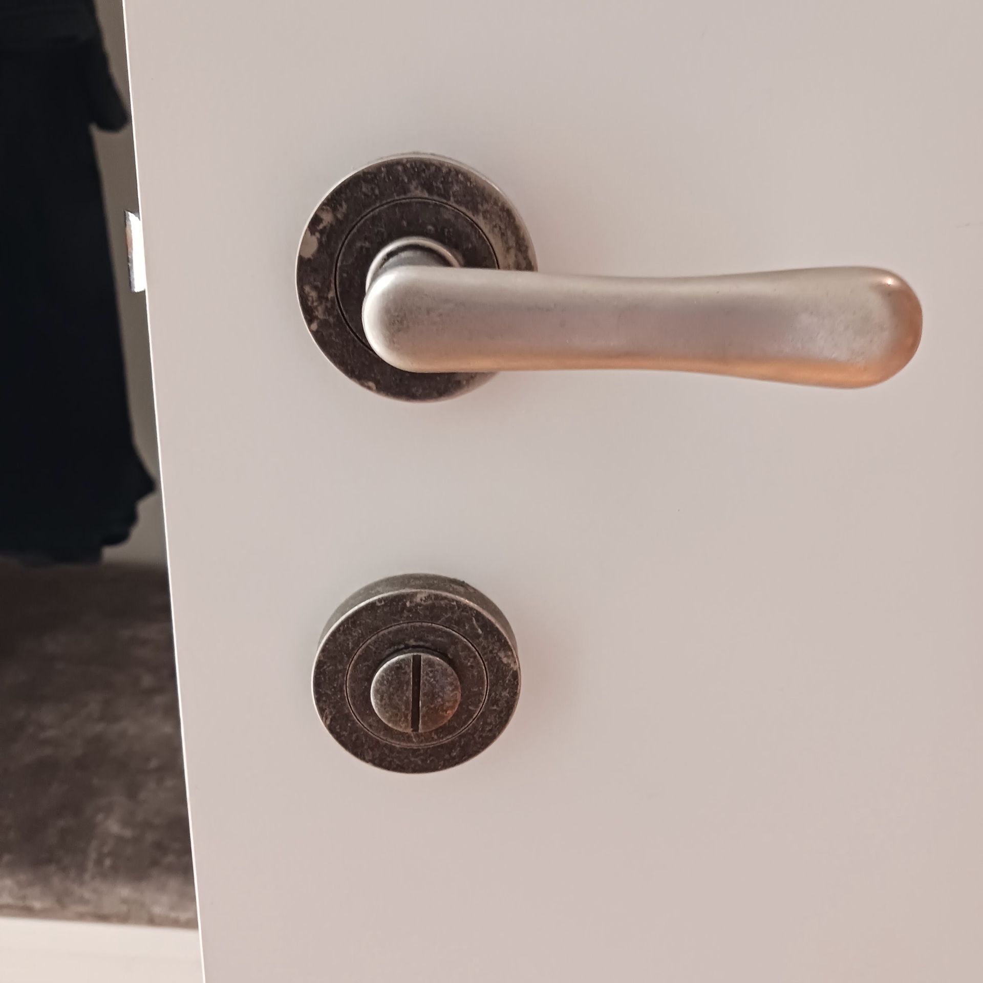 Door with a tarnished, silver lever handle and circular lock on a white door— Yamba Locksmiths in Yamba, NSW