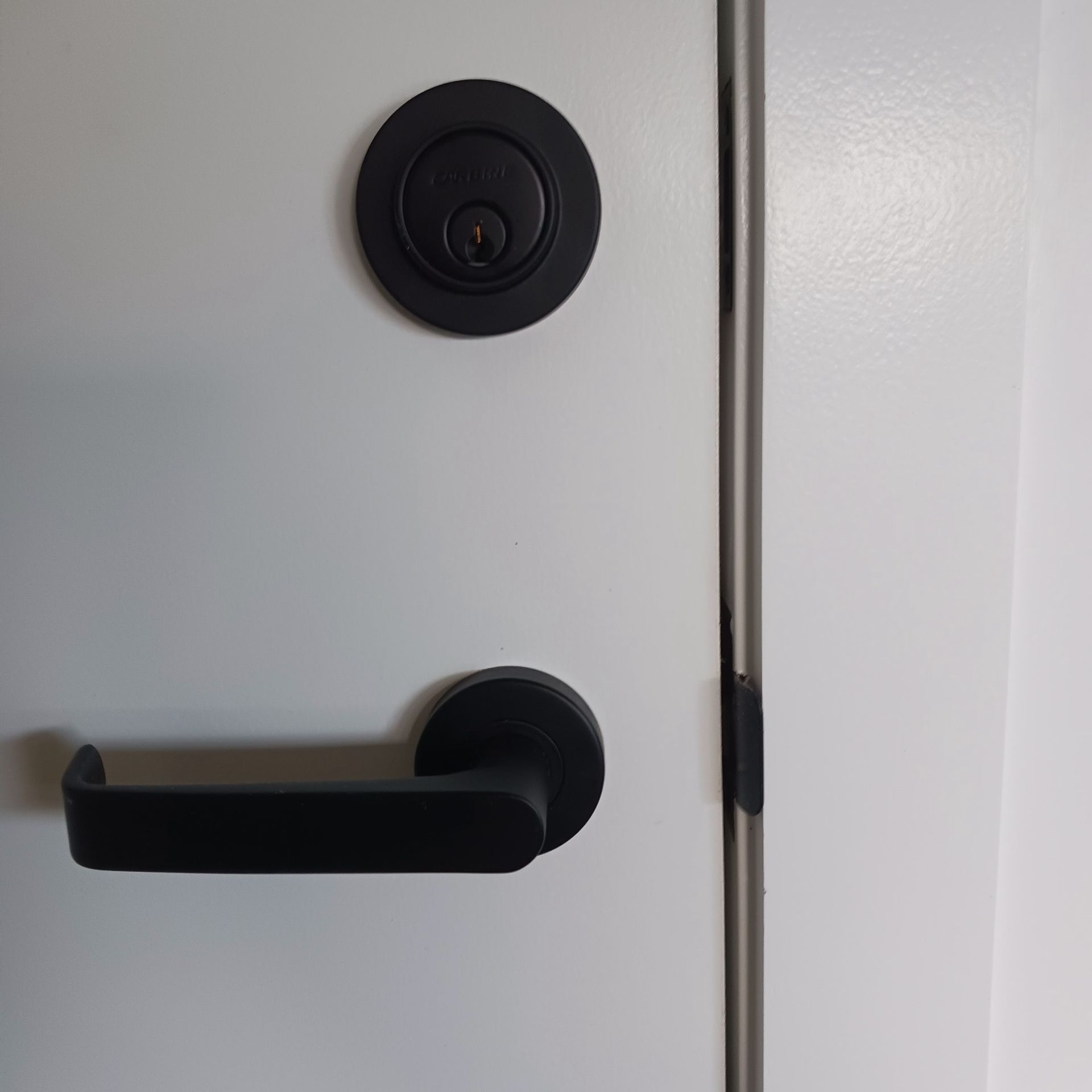 Black door handle and deadbolt on a white door— Yamba Locksmiths in Yamba, NSW