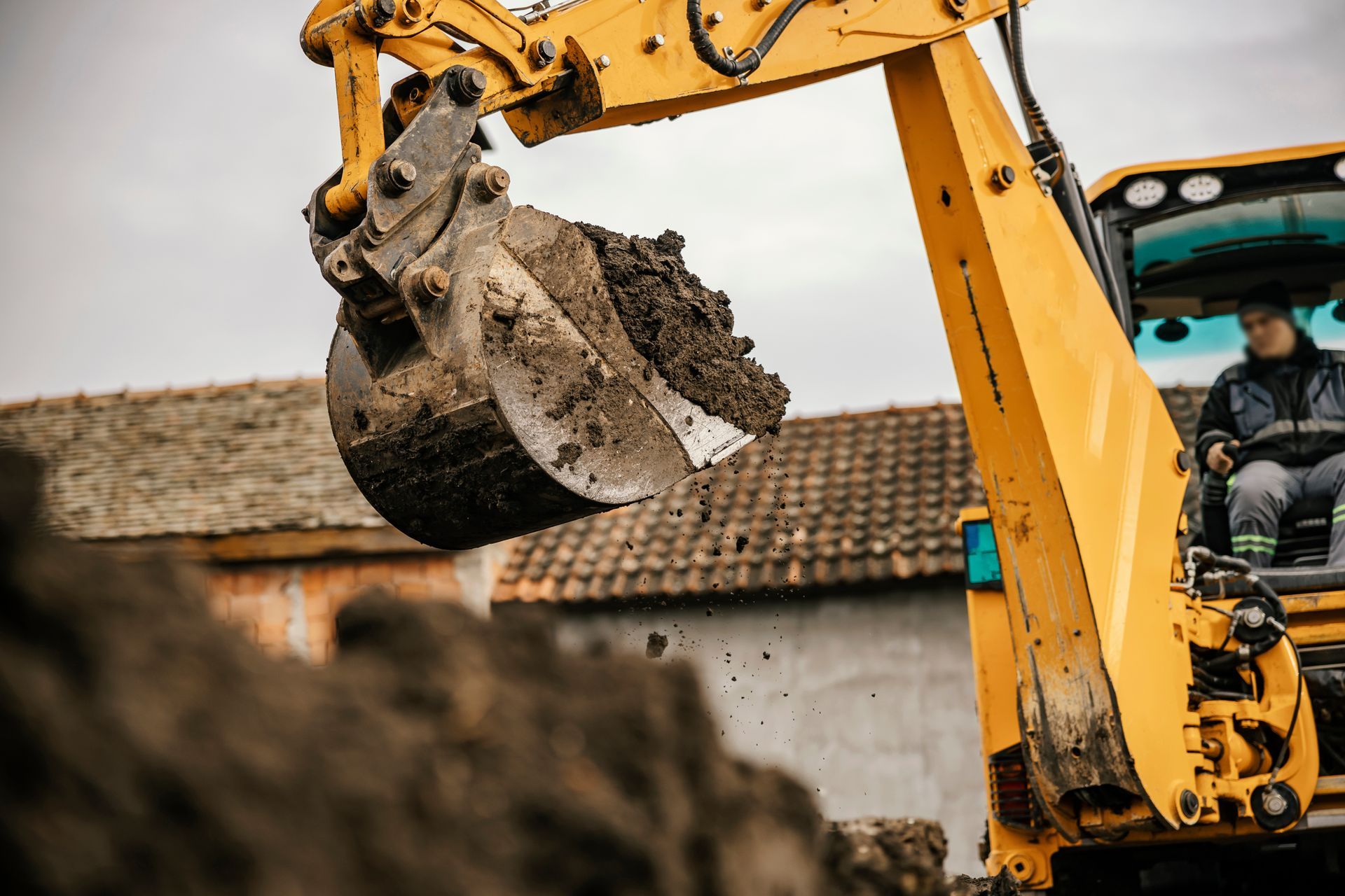 A man is driving a yellow excavator on a construction site.