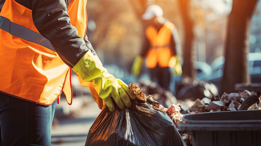 A person wearing gloves is holding a trash bag.