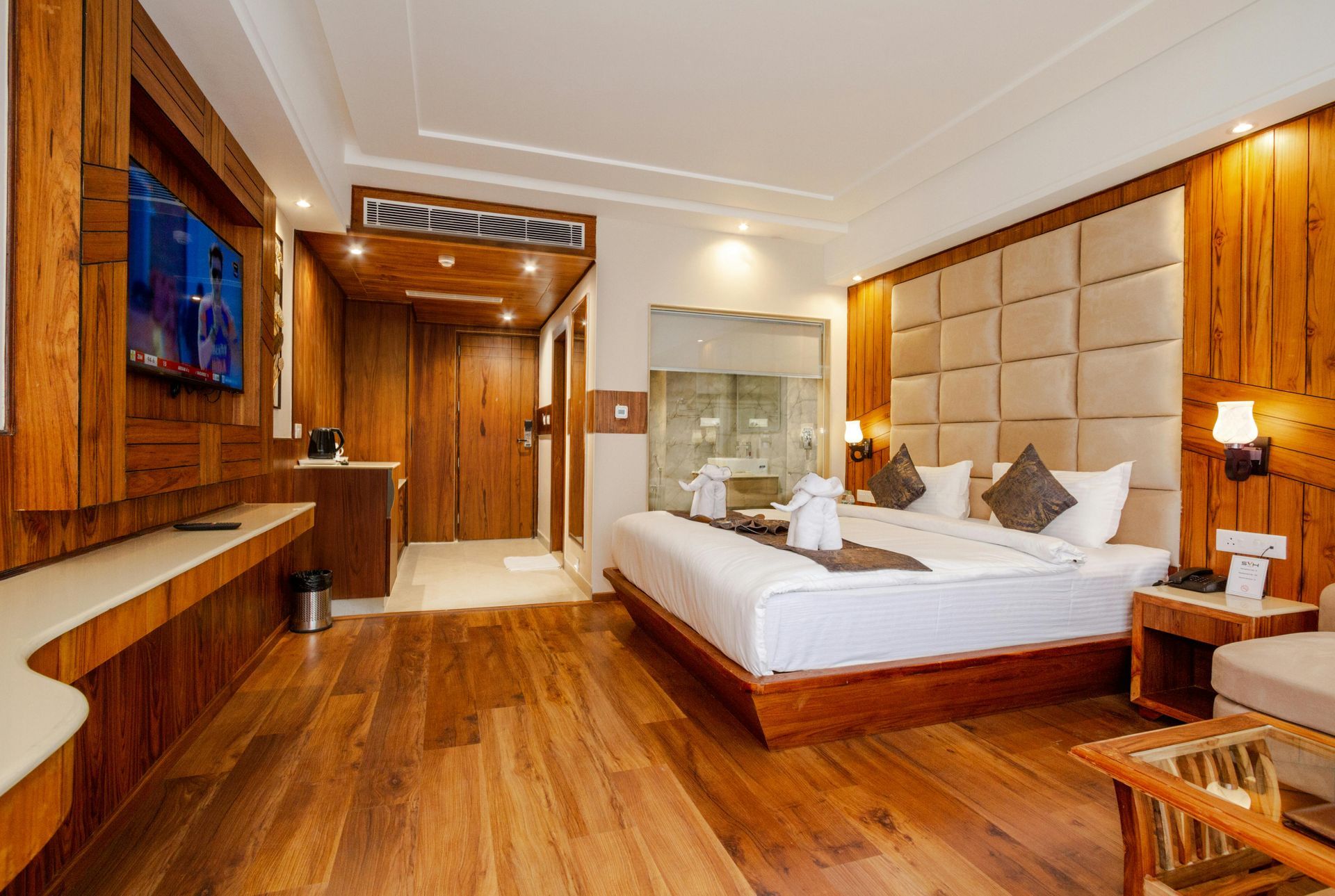 A hotel room with a bed , couch , table and laptop after refurbishment.