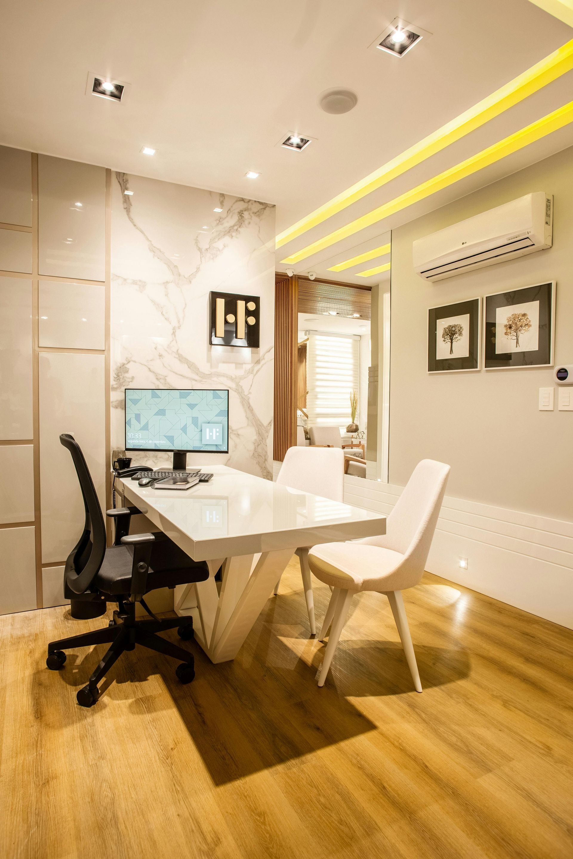 Modern office with white desk, computer, and chairs. Wooden floor and marble wall.
