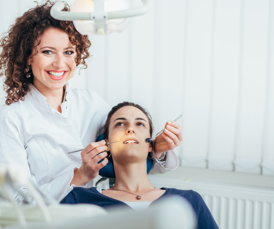 Dental patient undergoing treatment while a clinician holds instruments in a bright clinic setting