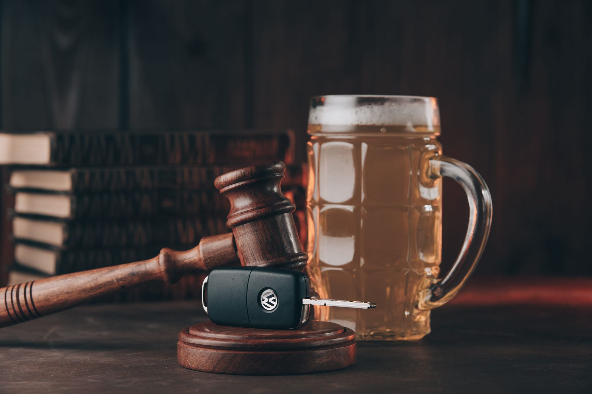 Wooden gavel beside a beer mug and car key on a dark desk