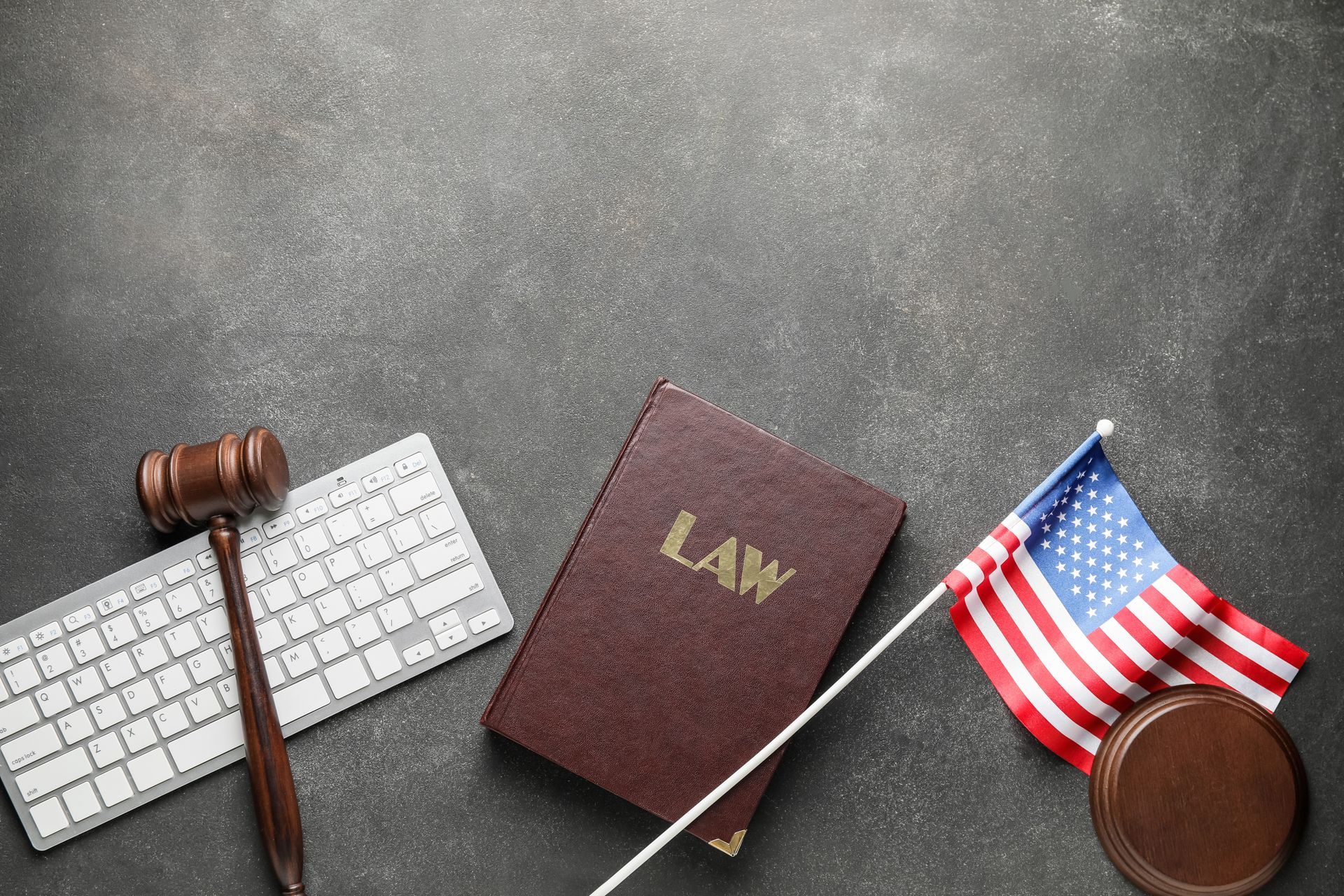 A law book , a gavel , a keyboard , and an american flag on a table.