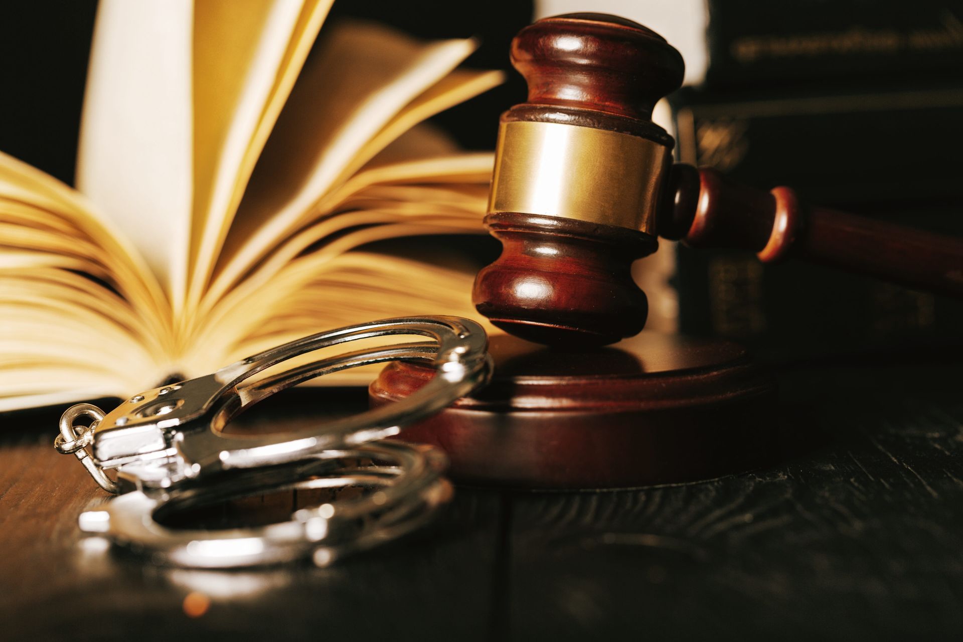 Judge’s gavel beside open law book and handcuffs on a desk