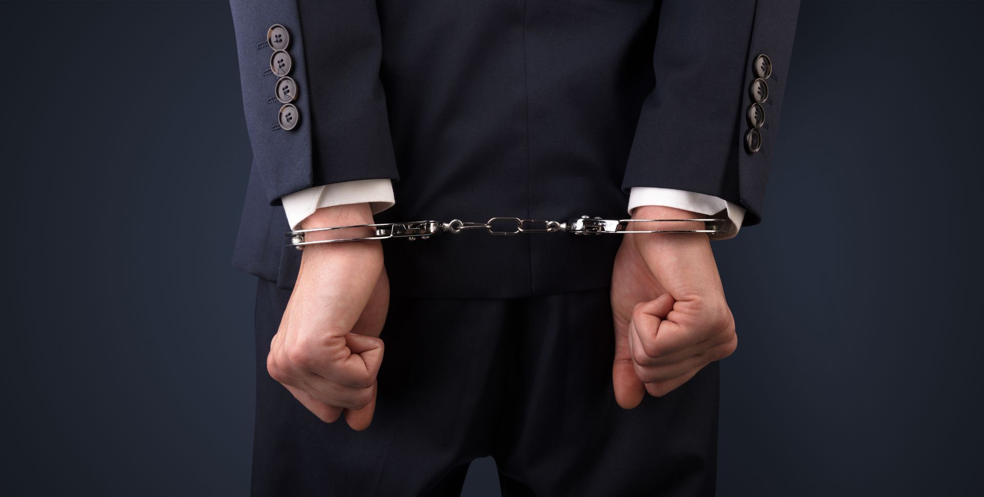 A man in a suit is wearing handcuffs.