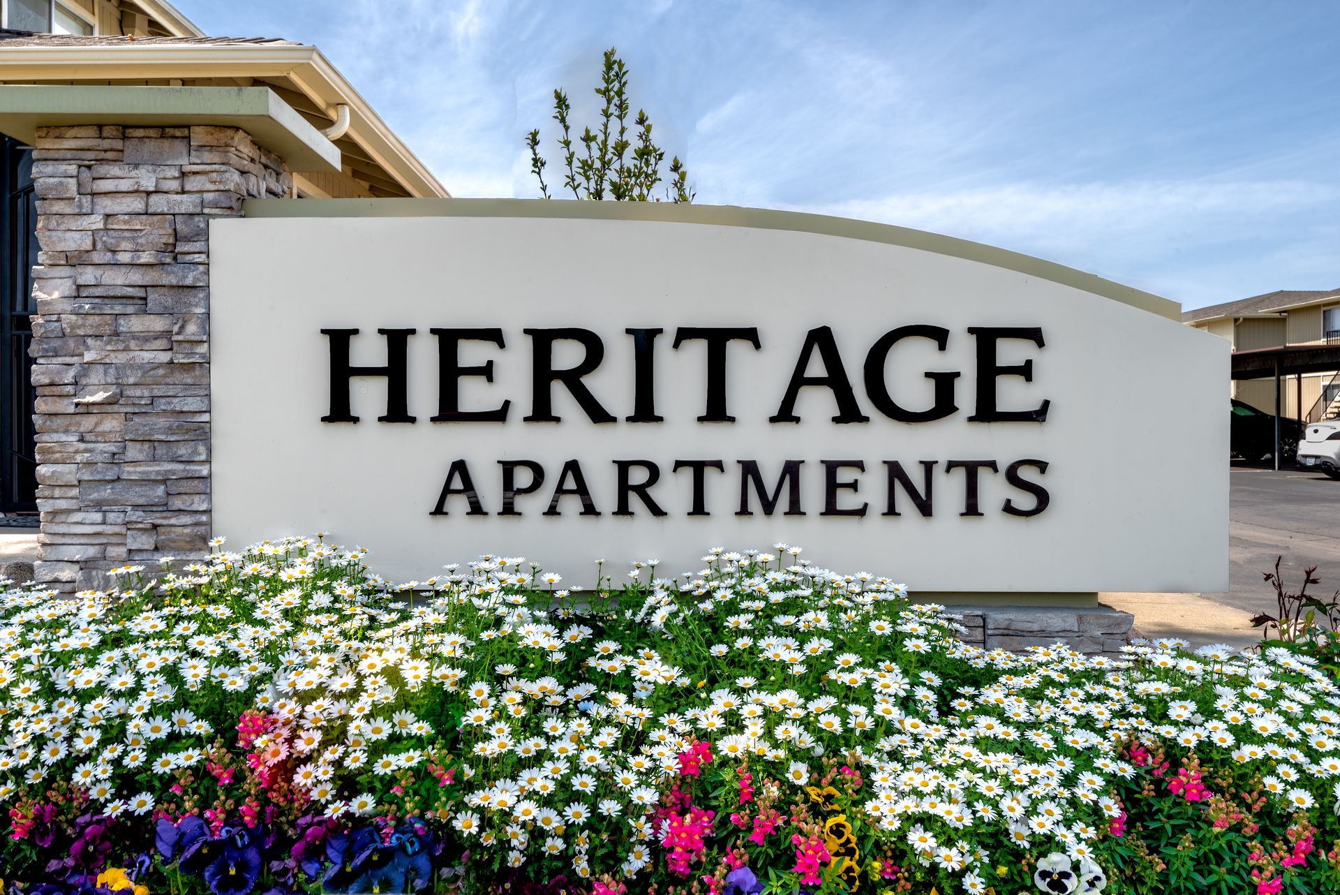 Sign for Heritage Apartments with flowering plants.