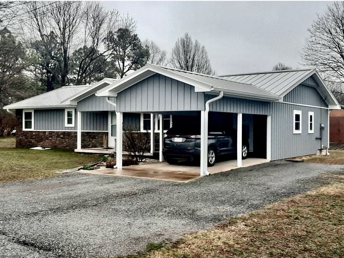 A truck is parked under a carport in front of a house.