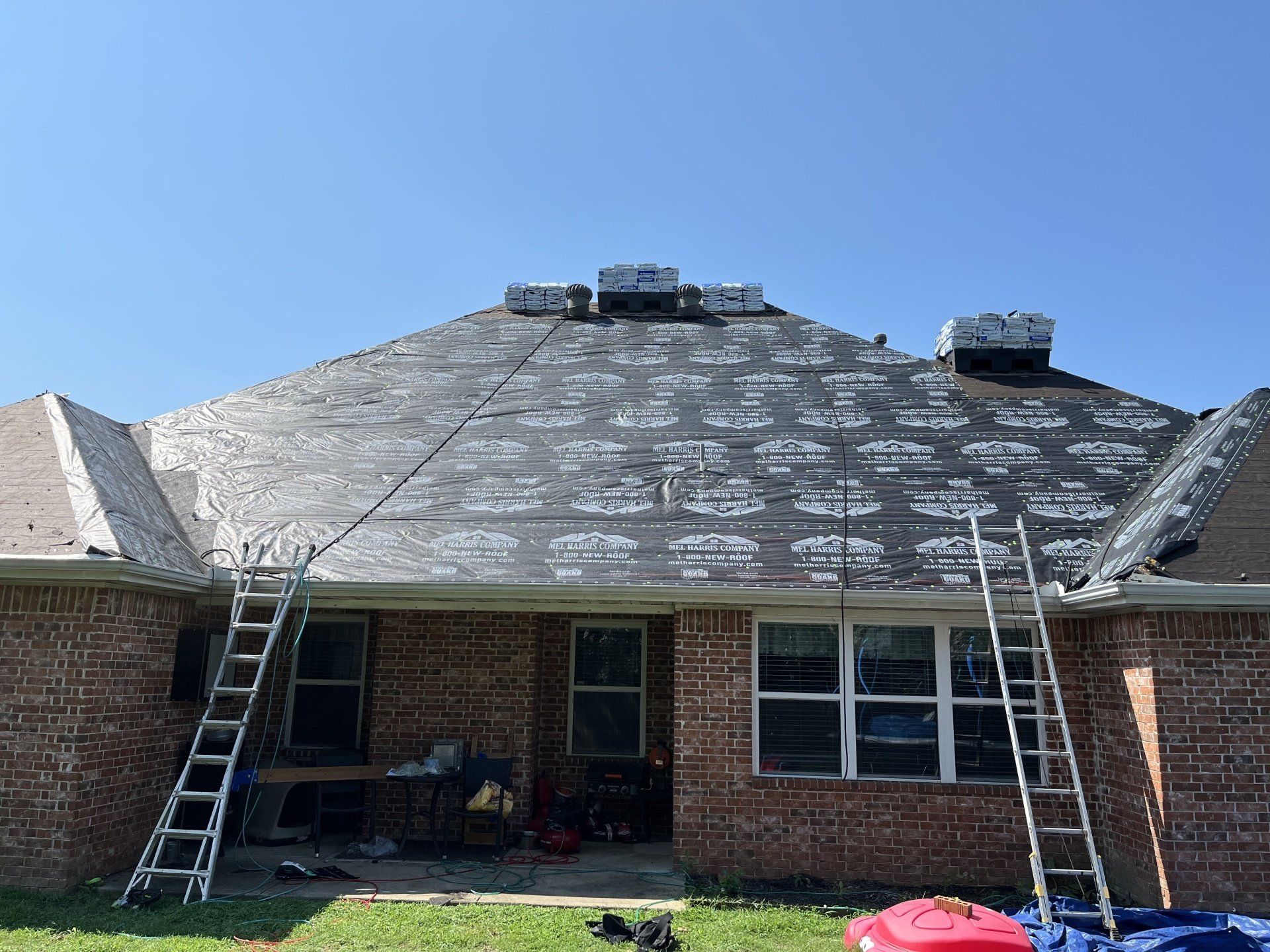 A brick house with a roof that is being repaired.