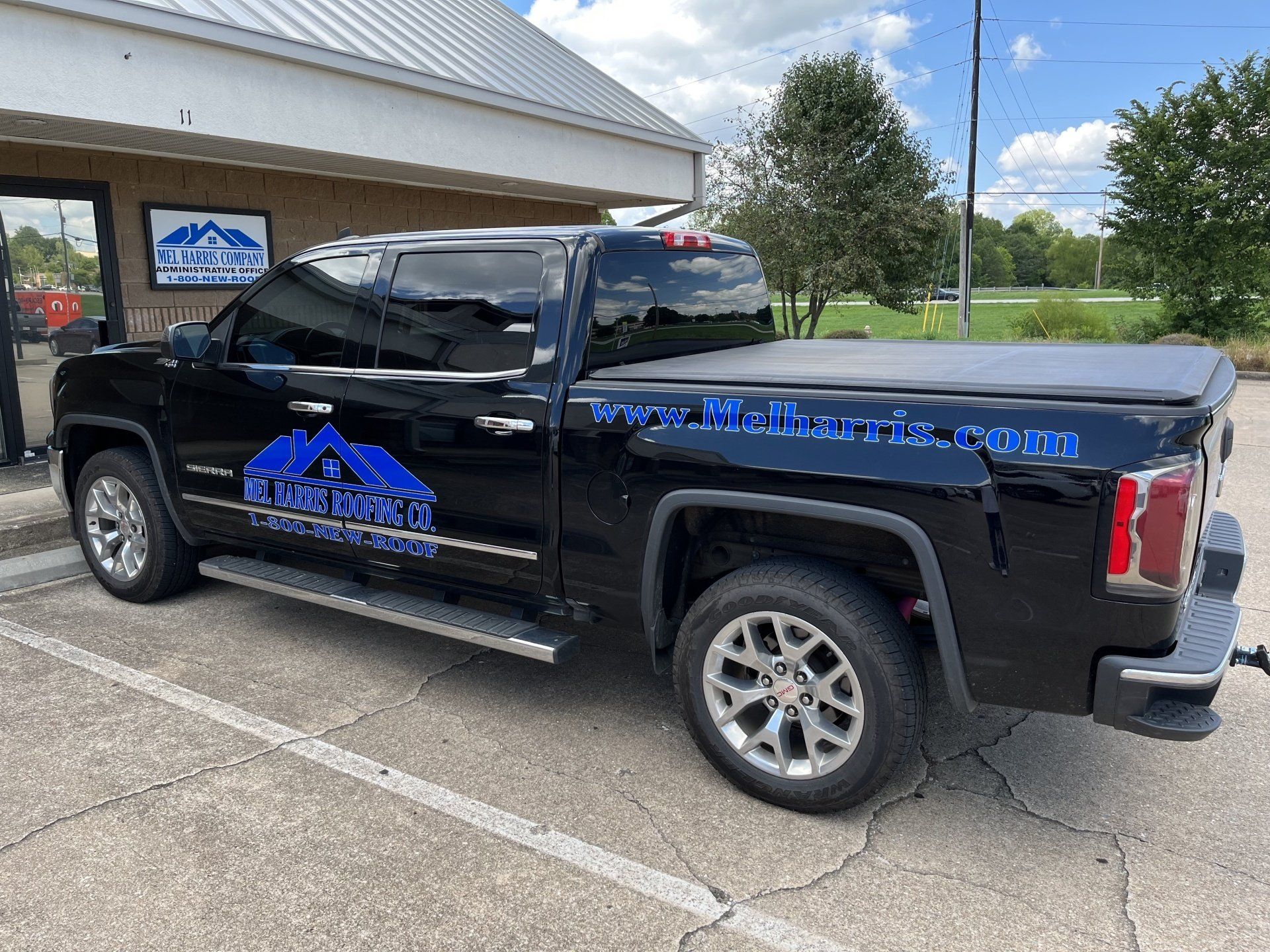 A black truck is parked in a parking lot in front of a building.