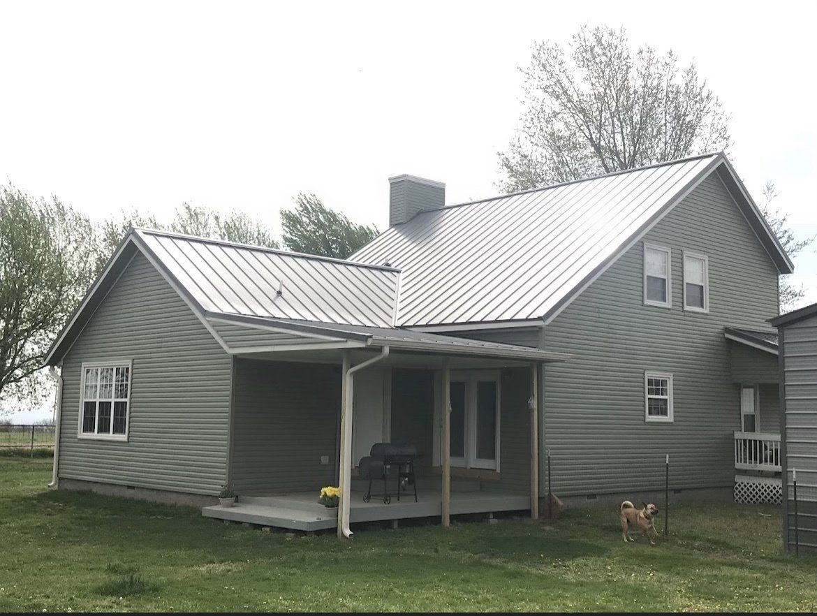 A small house with a metal roof and a porch.