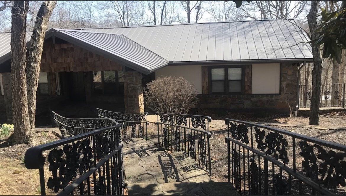 A house with a metal roof and a wrought iron fence in front of it.