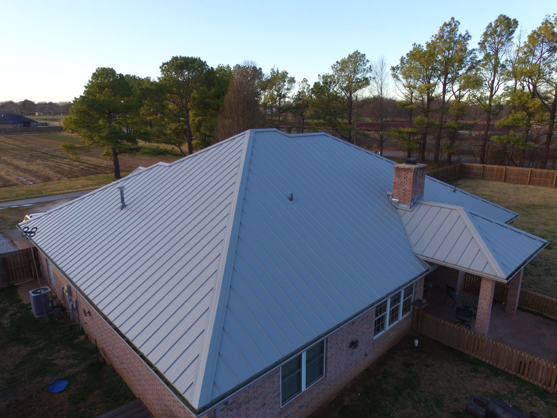 An aerial view of a house with a metal roof and a chimney.