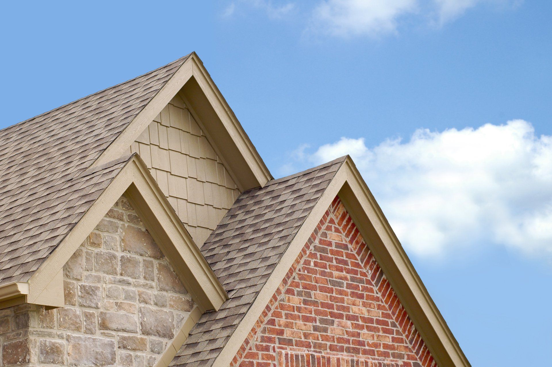 The roof of a brick house with a blue sky in the background.