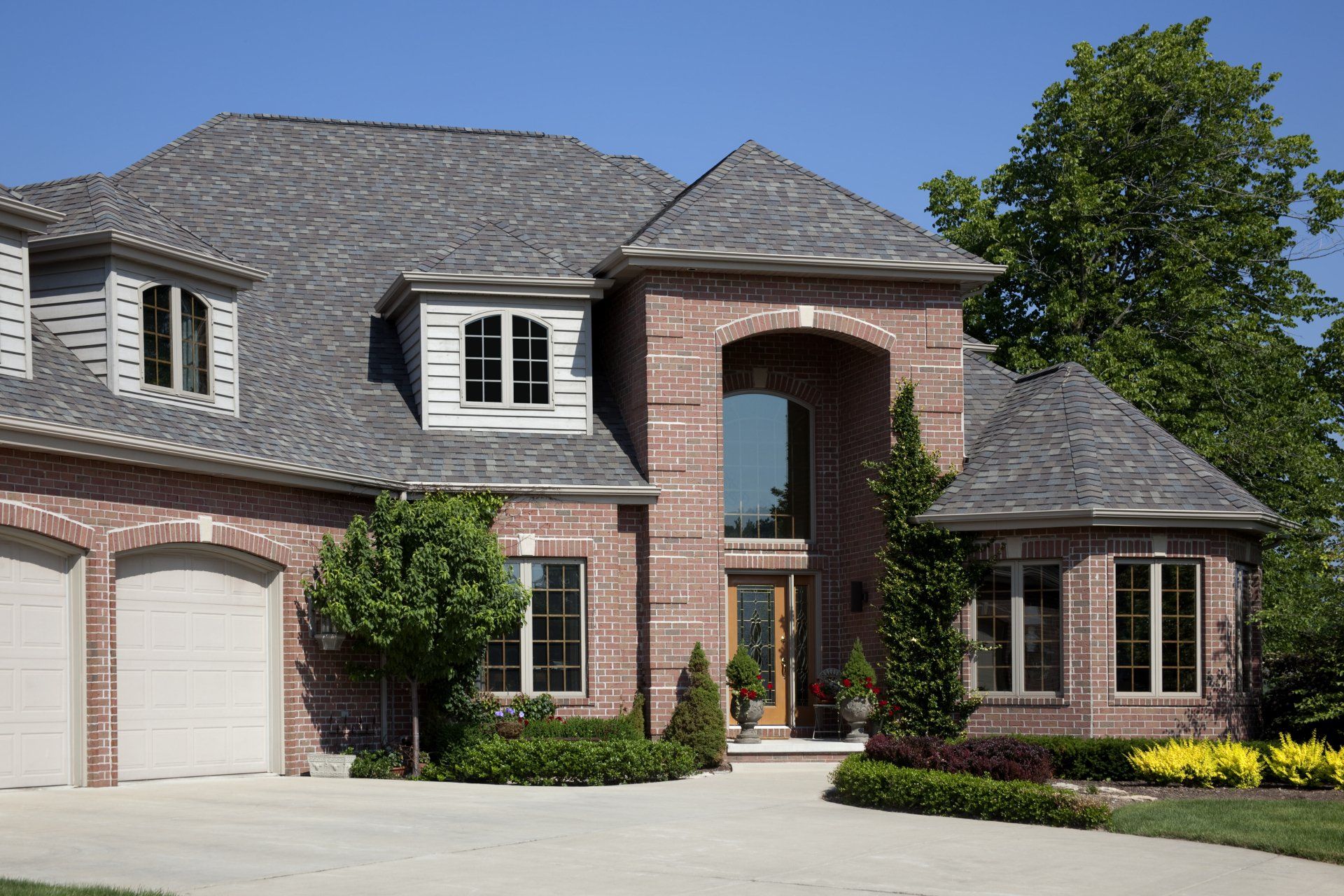 A large brick house with two garages and a gray roof