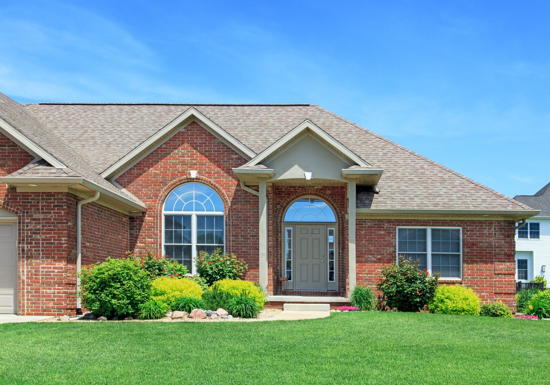 A large brick house with a lush green lawn in front of it.