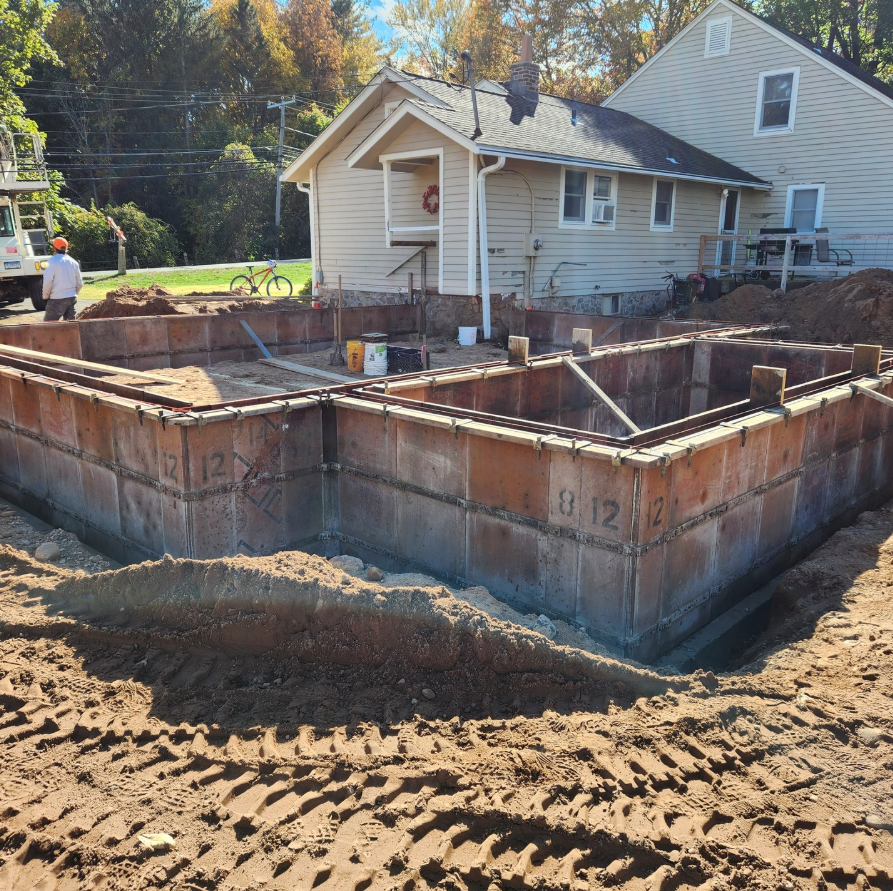 A man is standing on a ladder painting the side of a house.