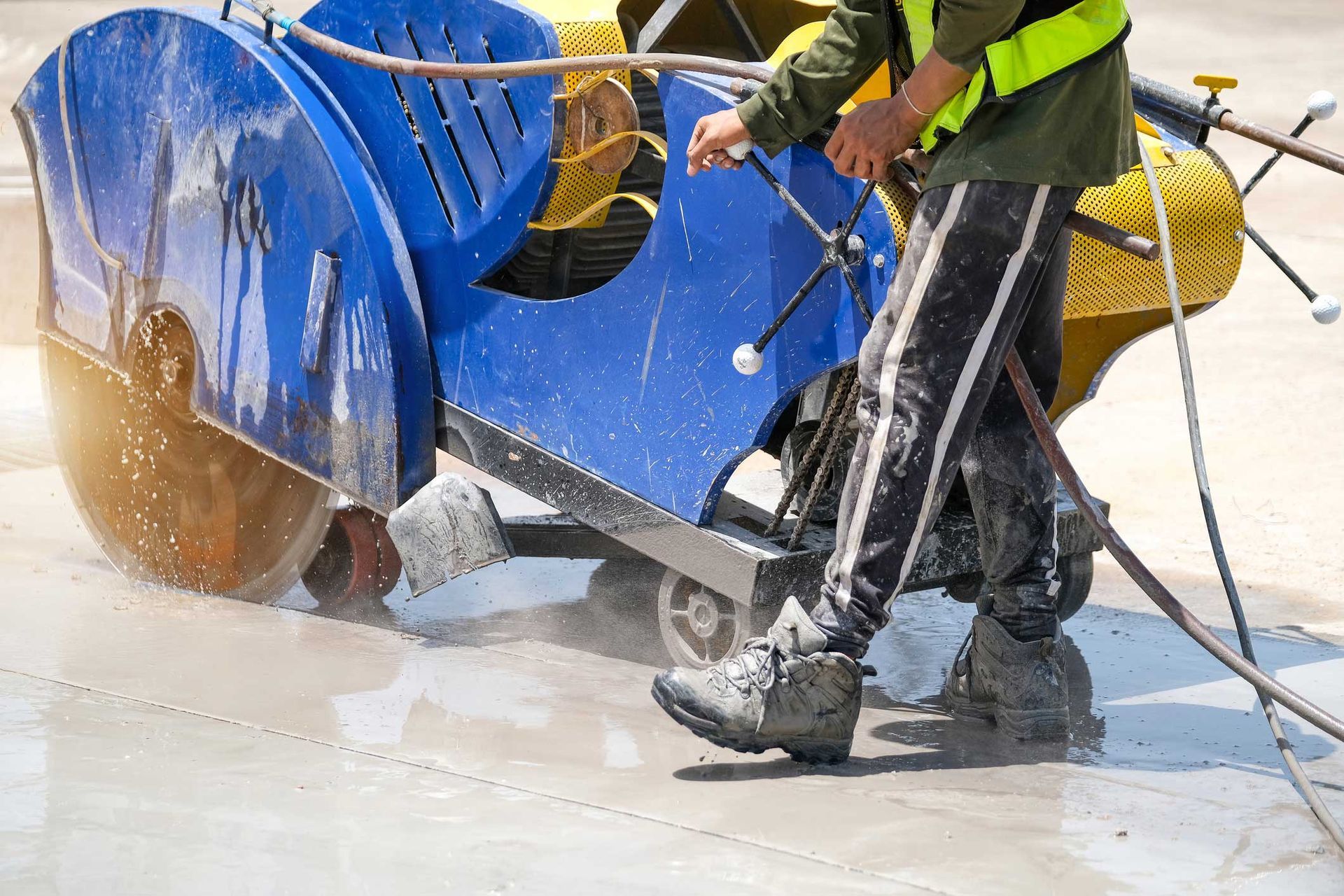 A man is using a cutting machine to cut concrete.