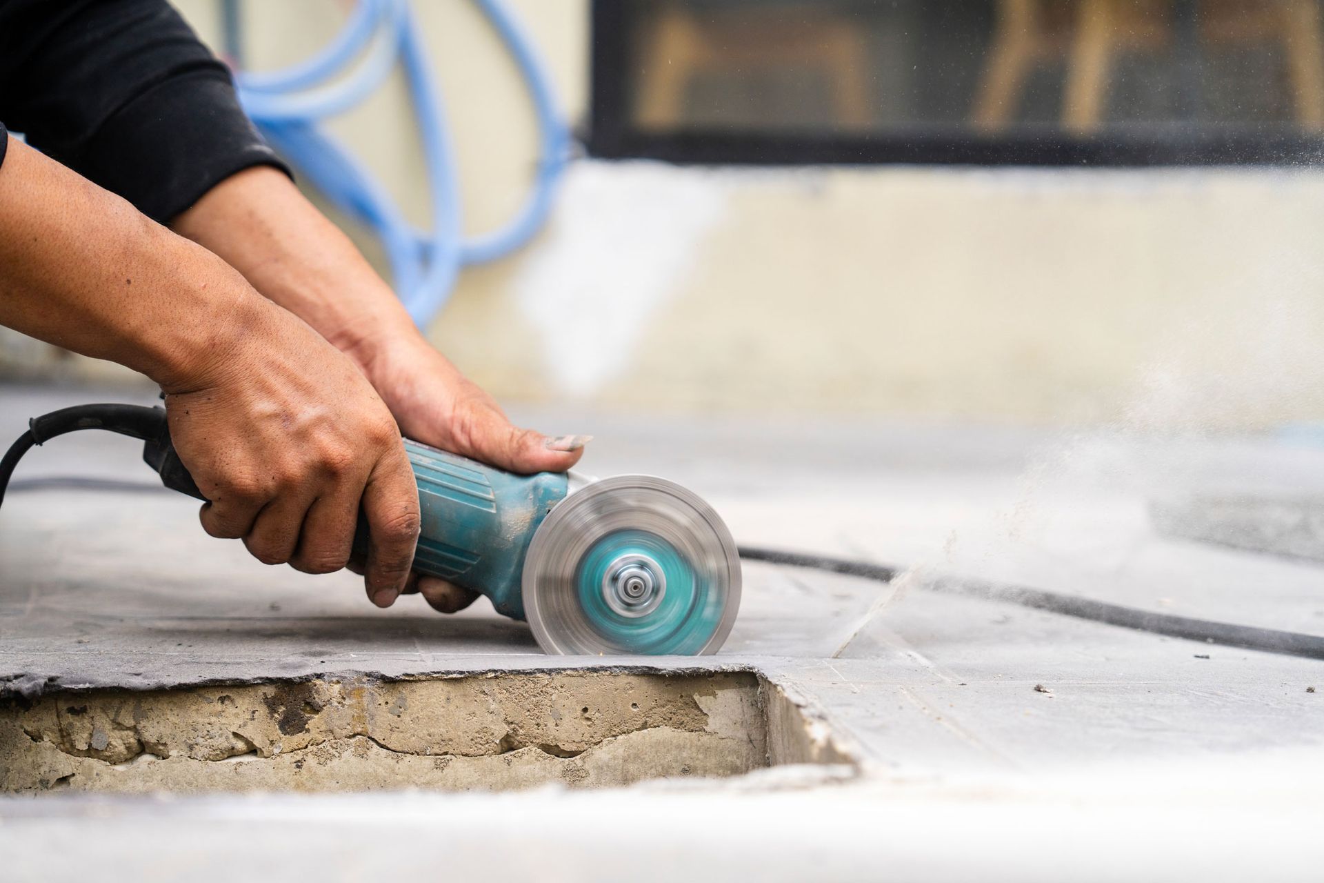 A man is using a grinder to cut concrete.