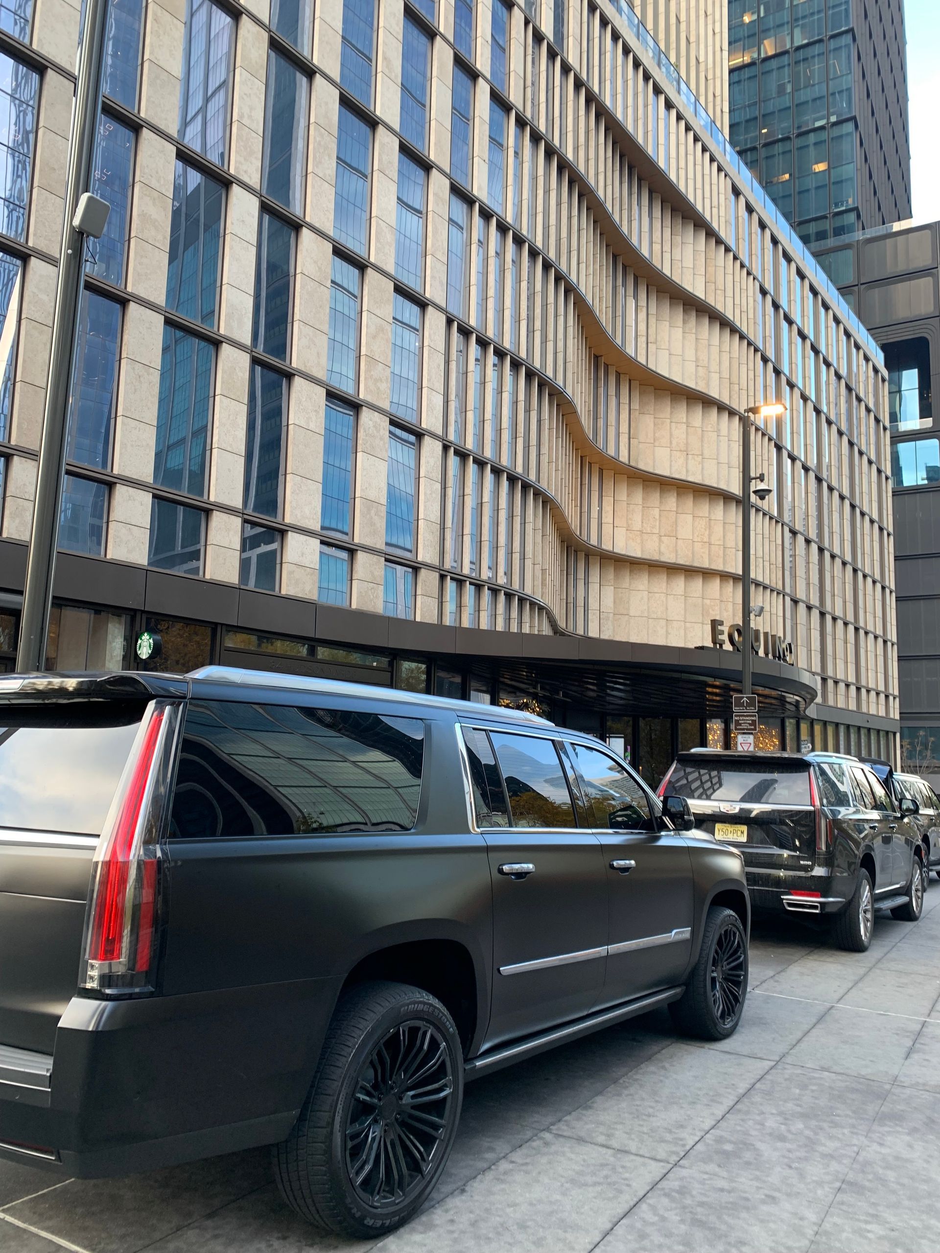A row of cars are parked in front of a building.