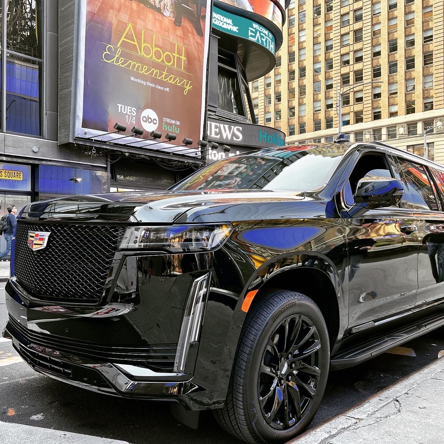 A black suv is parked on the side of the road in front of a building.