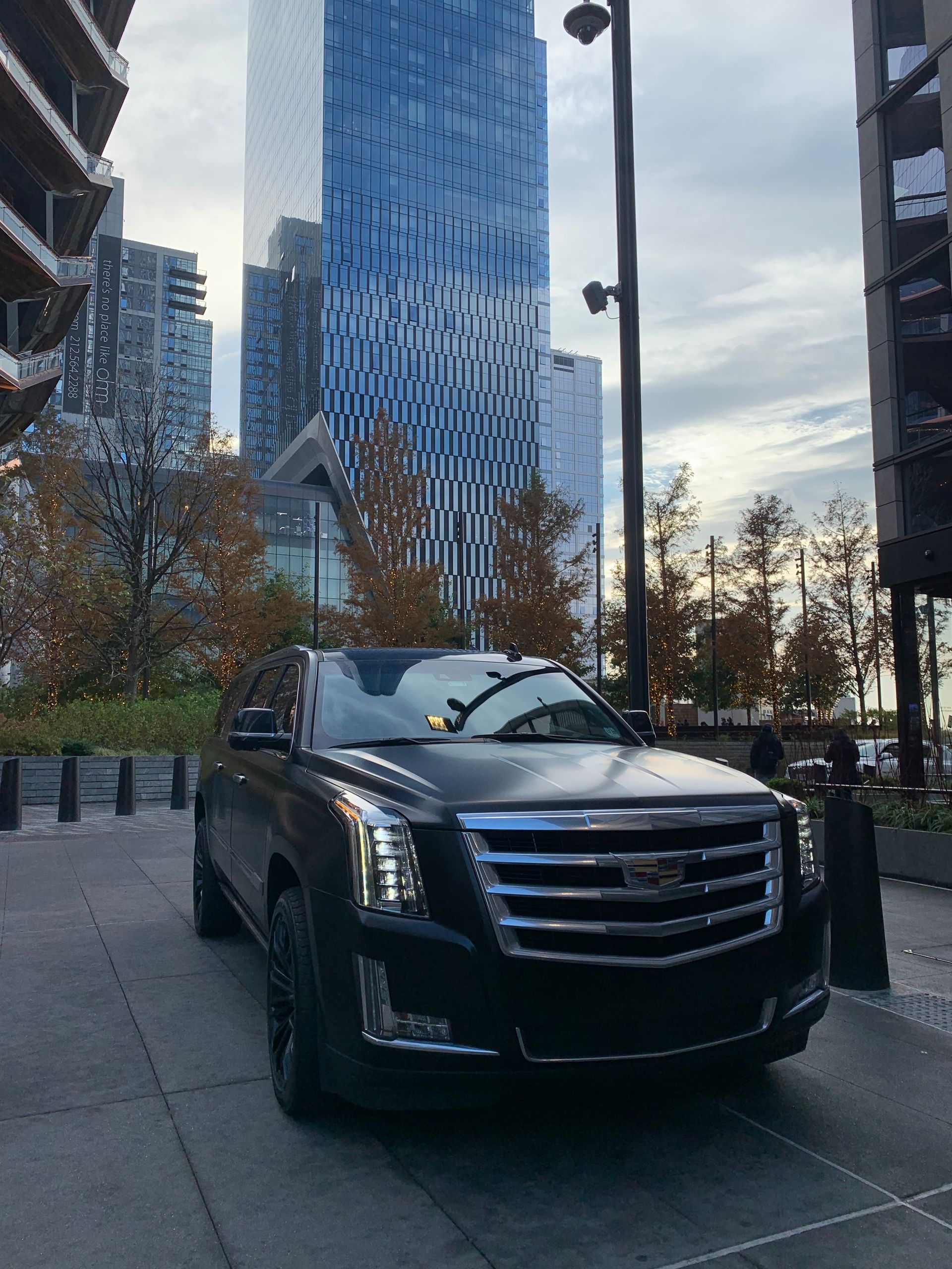 A black cadillac is parked in front of a tall building