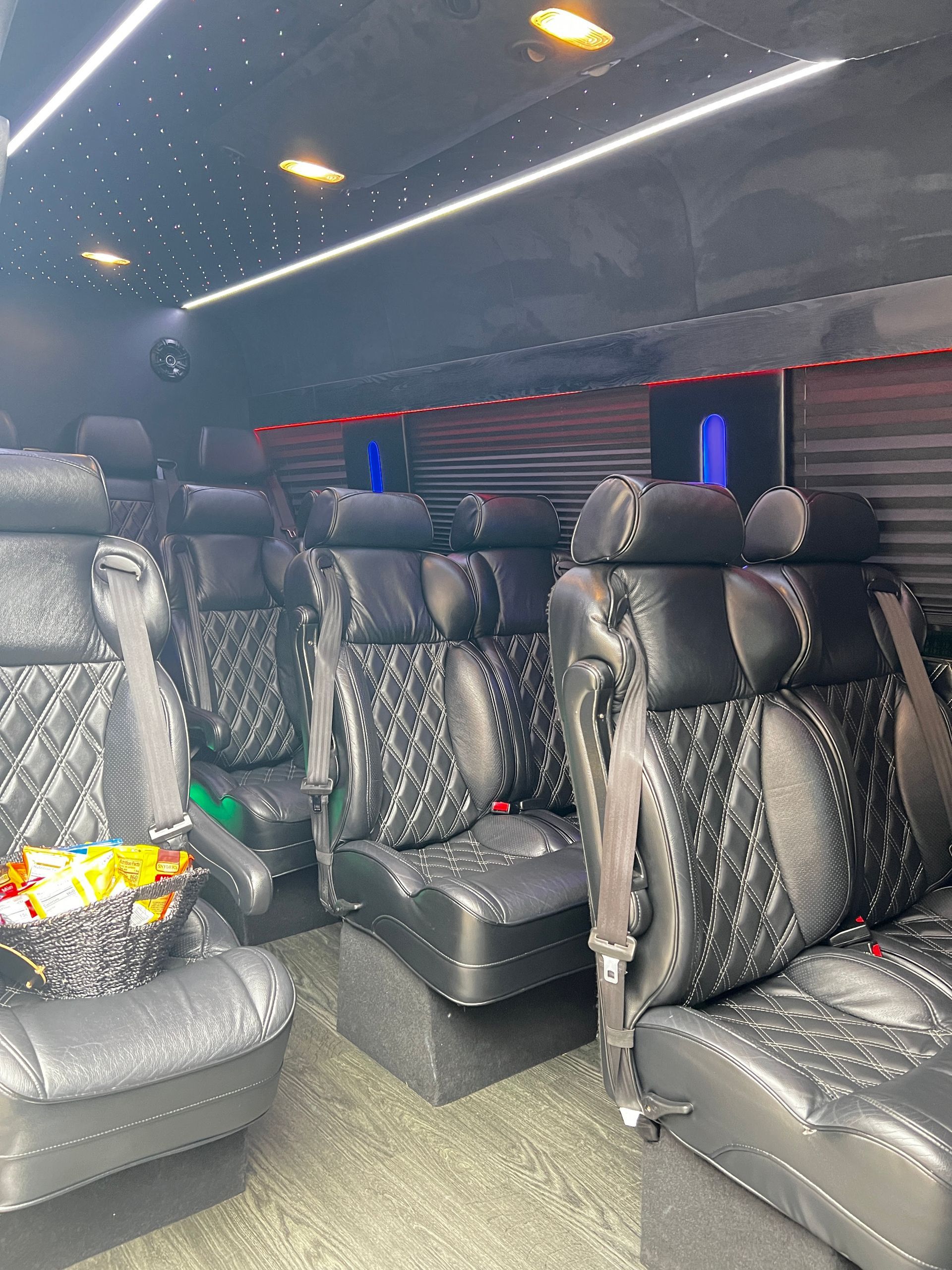 The inside of a van with lots of black seats and a basket of food.