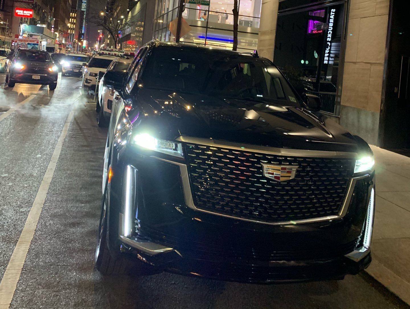 A black cadillac is parked on the side of the road
