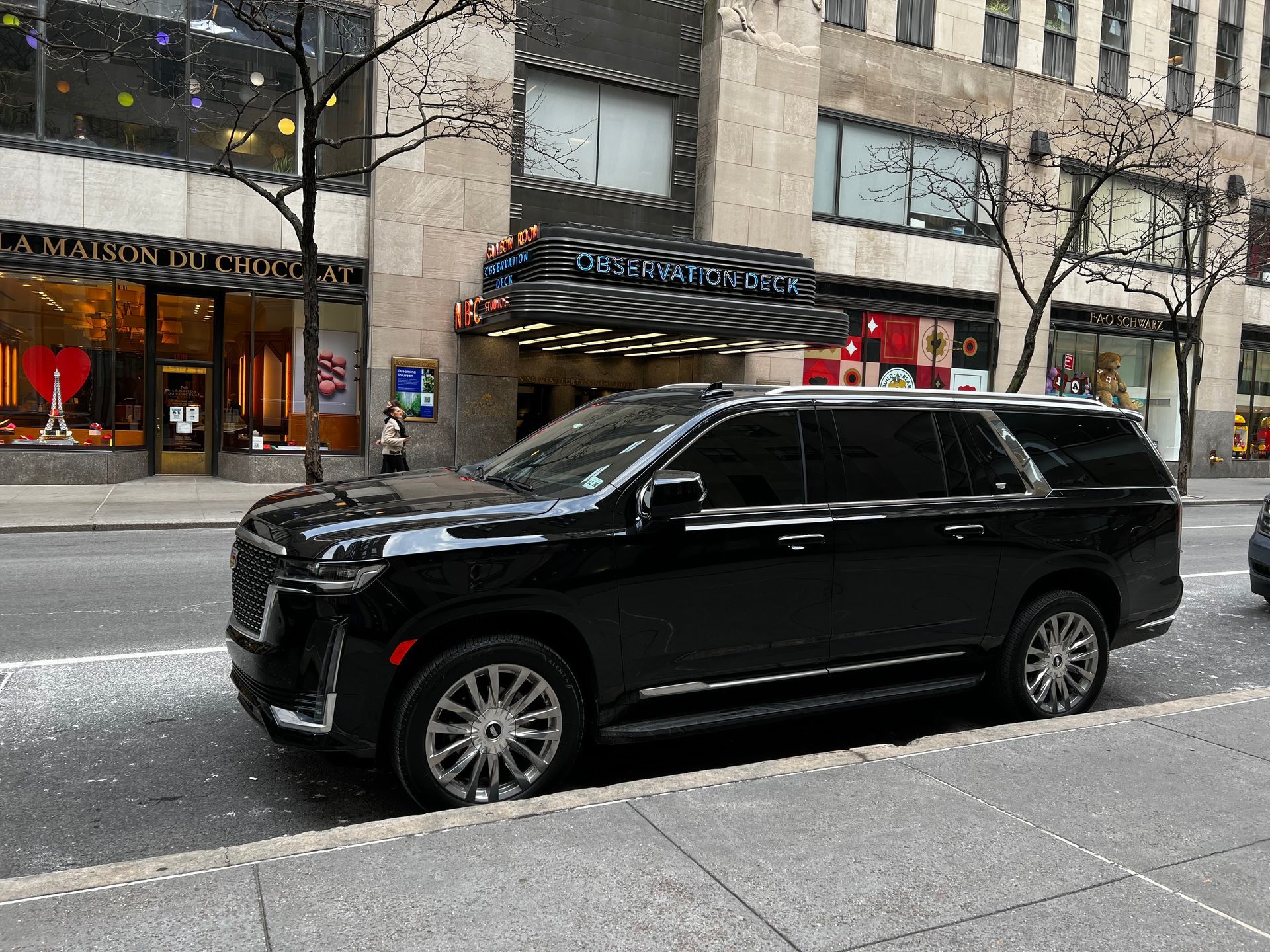 A black suv is parked on the side of the road in front of a building.