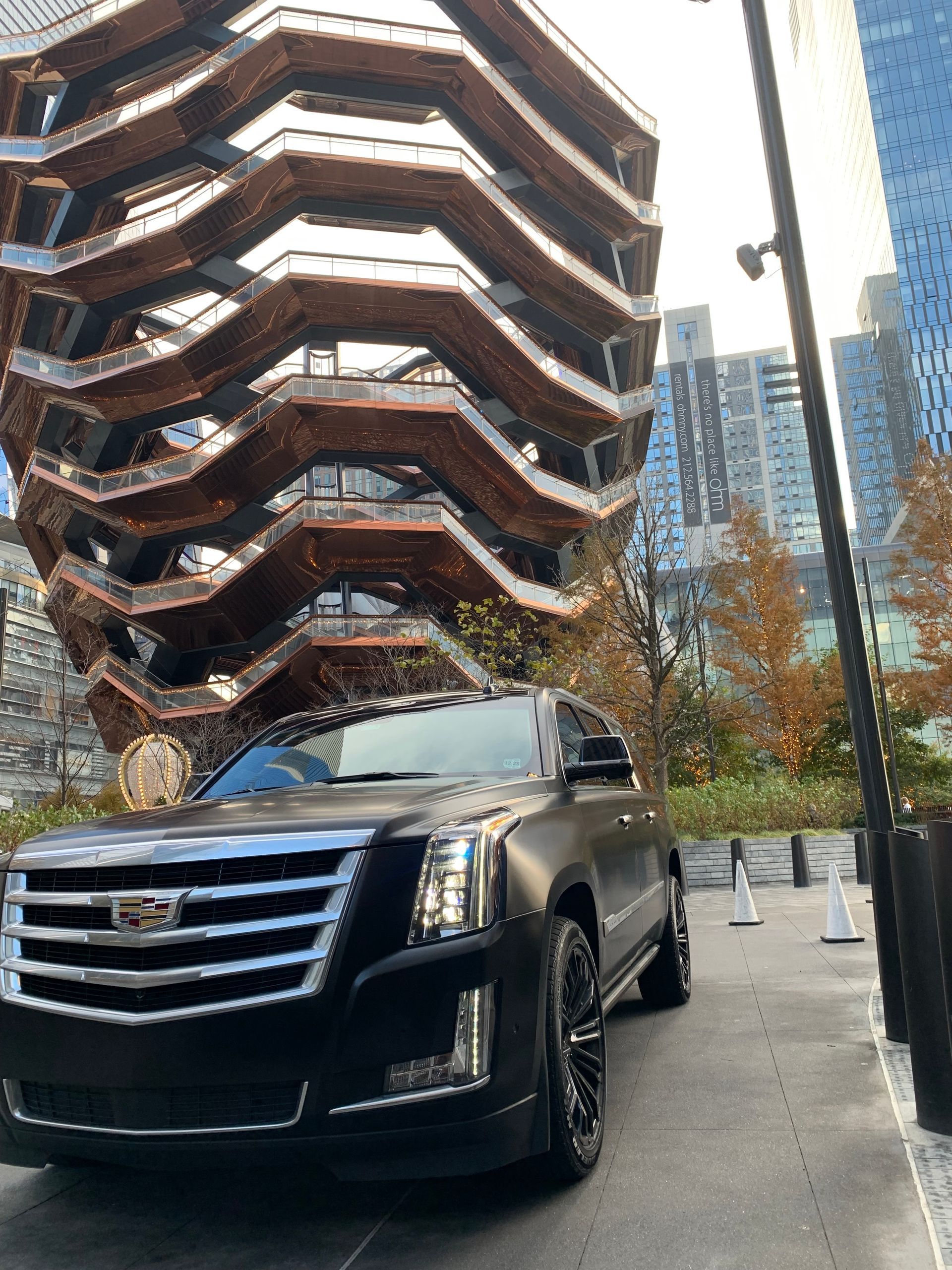 A black cadillac is parked in front of a large building.