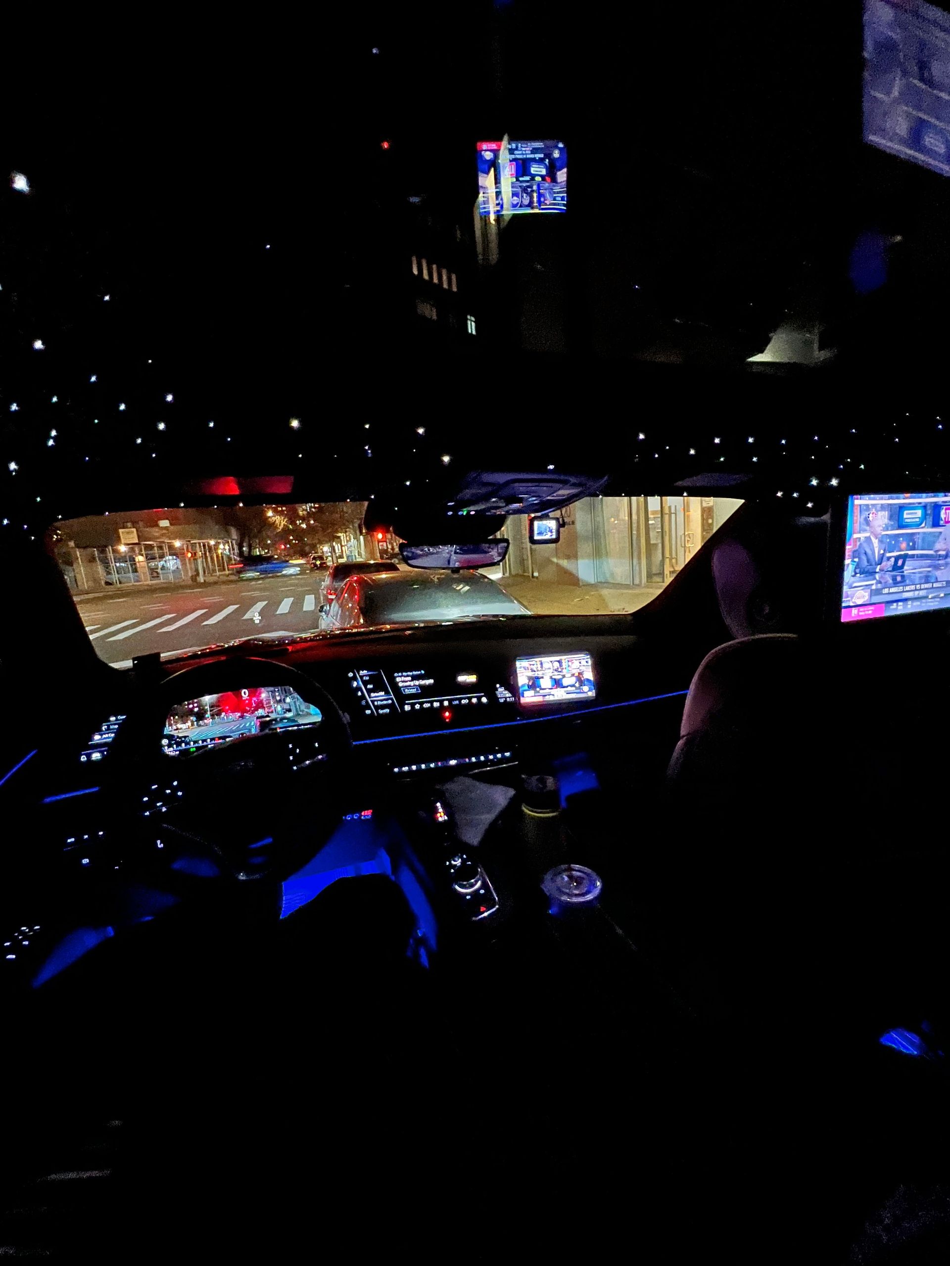 A person is sitting in the driver 's seat of a car at night.