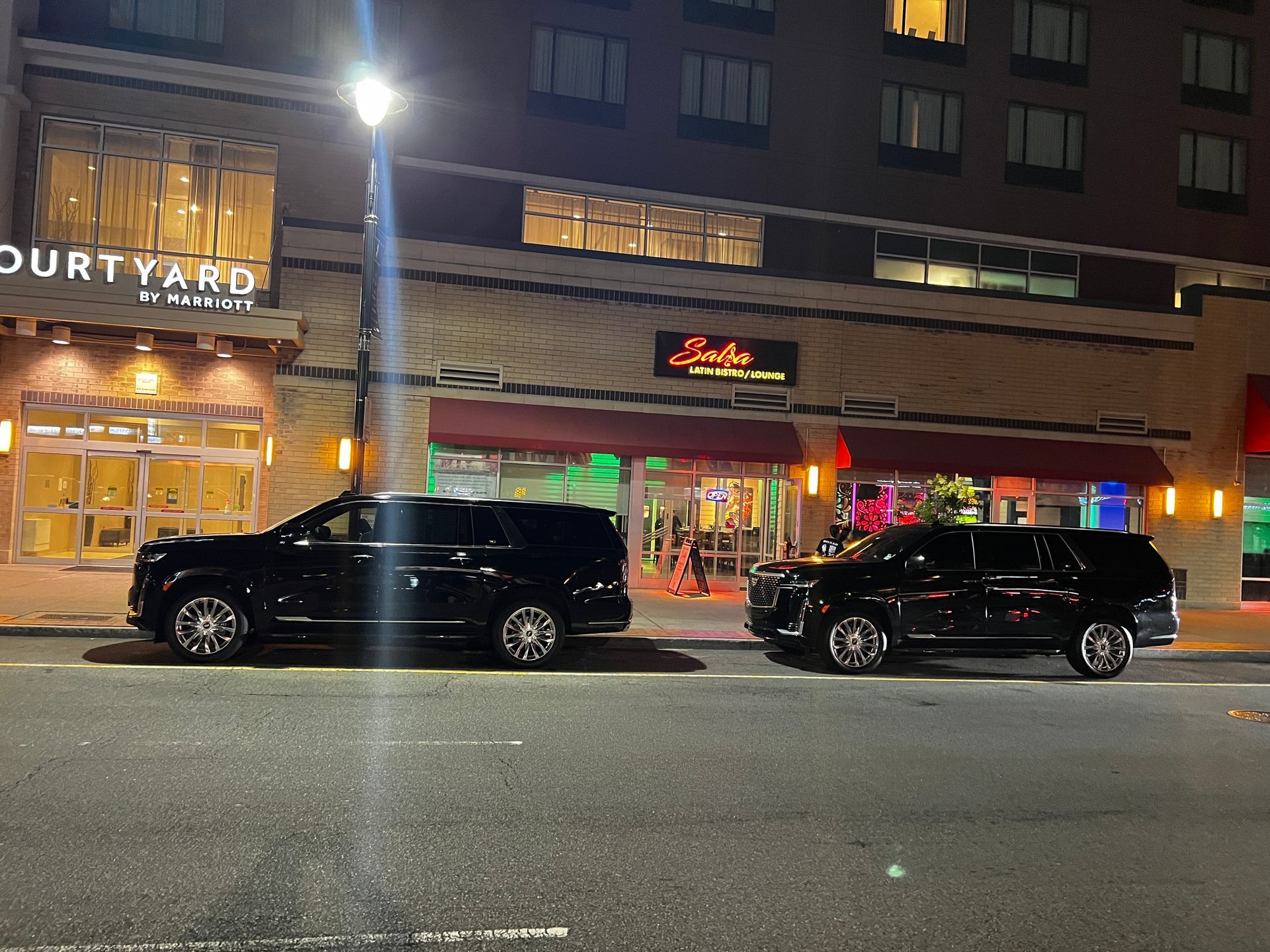 Two cars are parked in front of a courtyard hotel