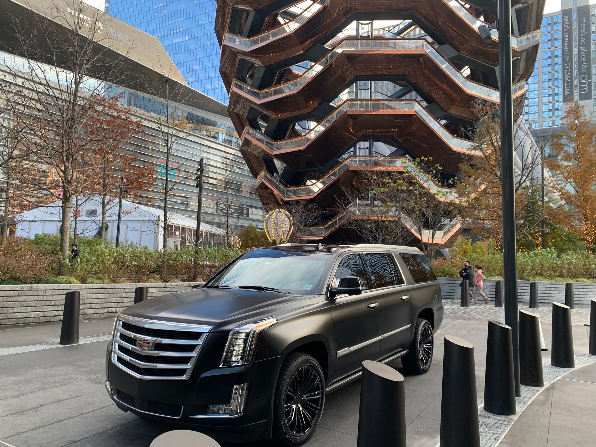 A black cadillac escalade is parked in front of a building.