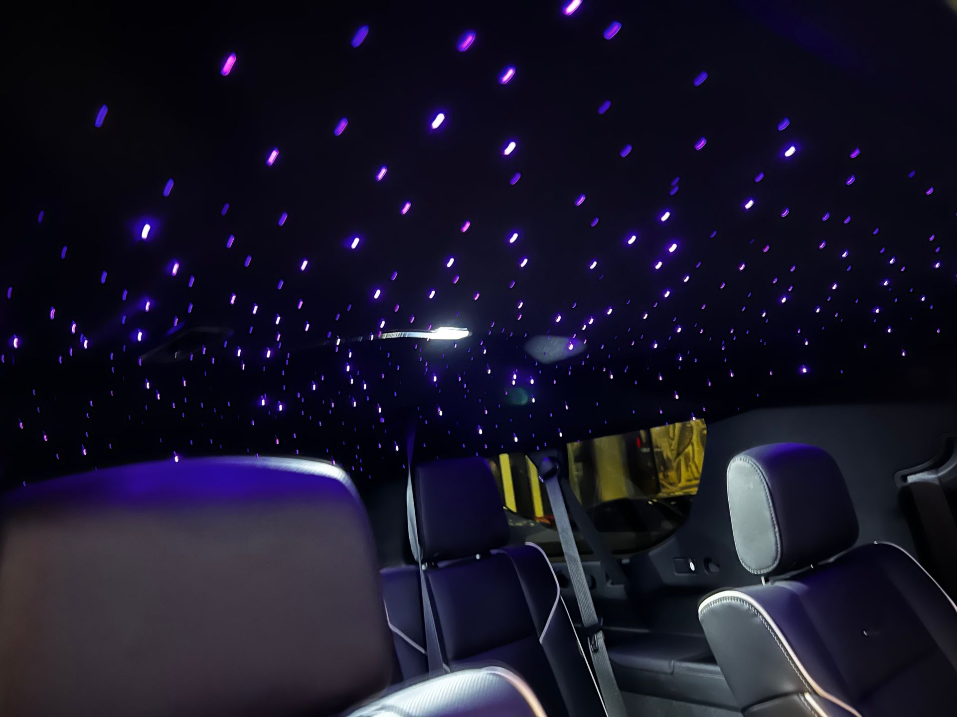 The ceiling of a car is lit up with purple lights.