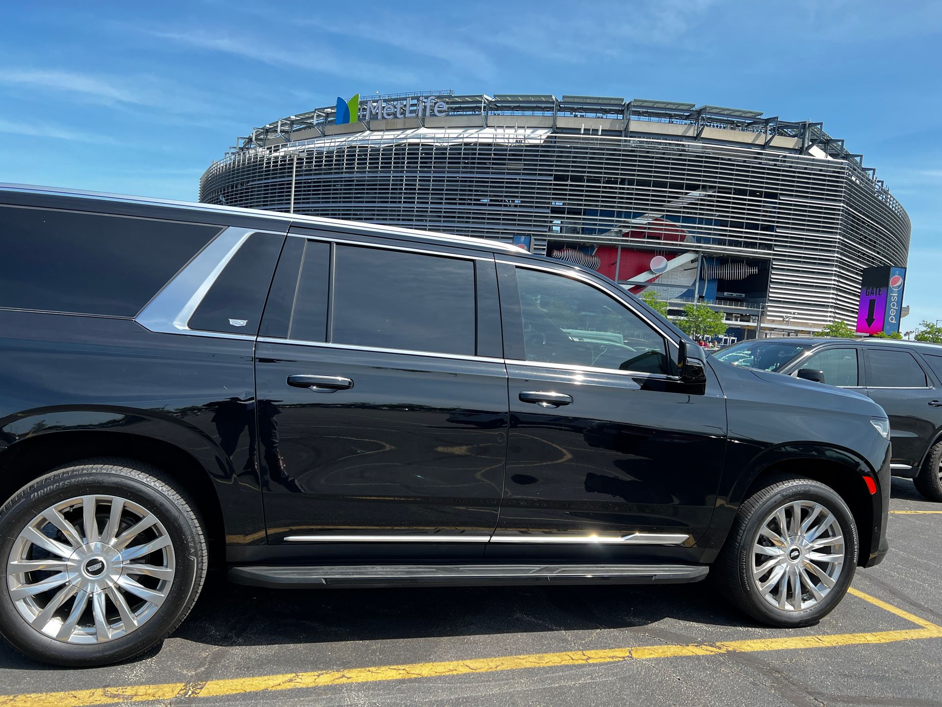 A black suv is parked in a parking lot in front of a stadium.