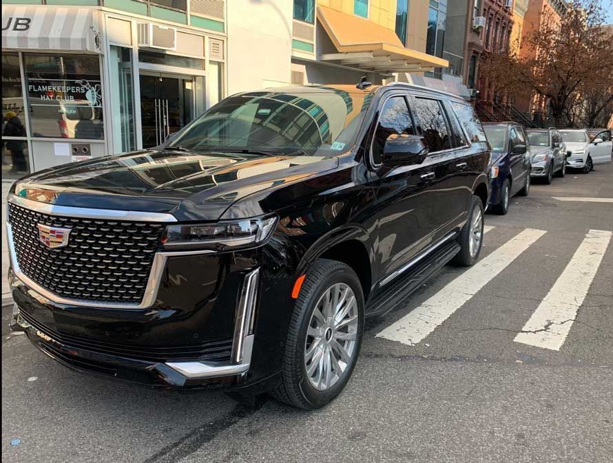 A black cadillac escalade is parked on the side of the road.