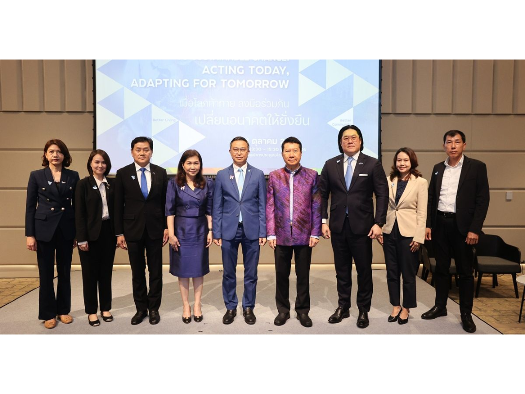 Group of people standing in front of a conference backdrop. They are formally dressed and smiling.