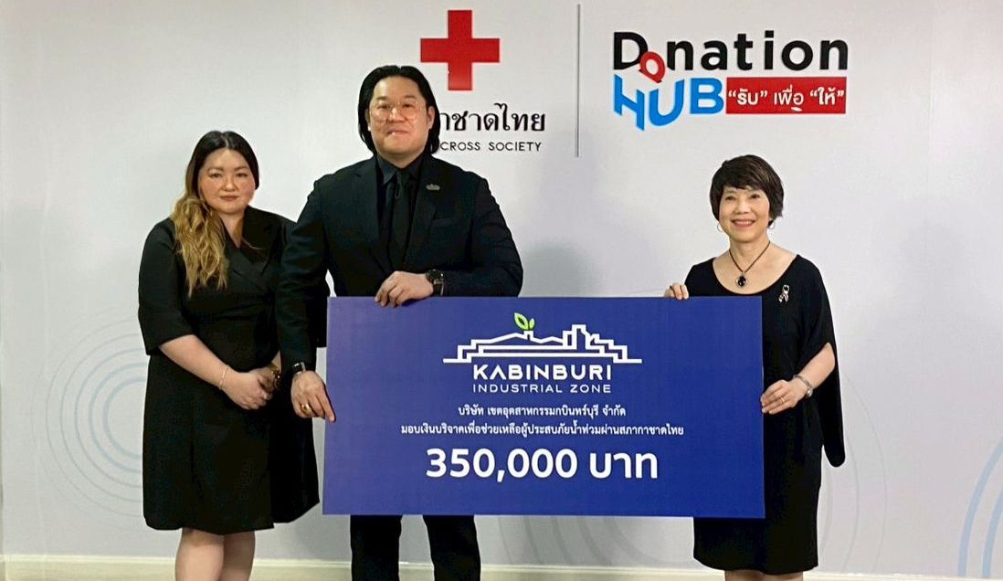 Three people hold a donation check for 350,000 baht. They stand in front of a donation hub and Red Cross sign.