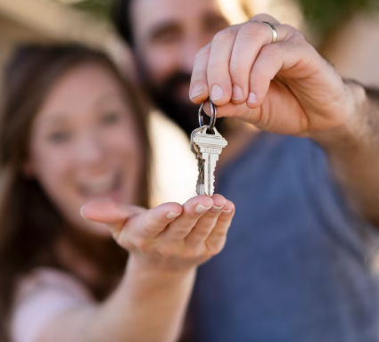 Pareja extendiendo las manos para recibir las llaves de casa.