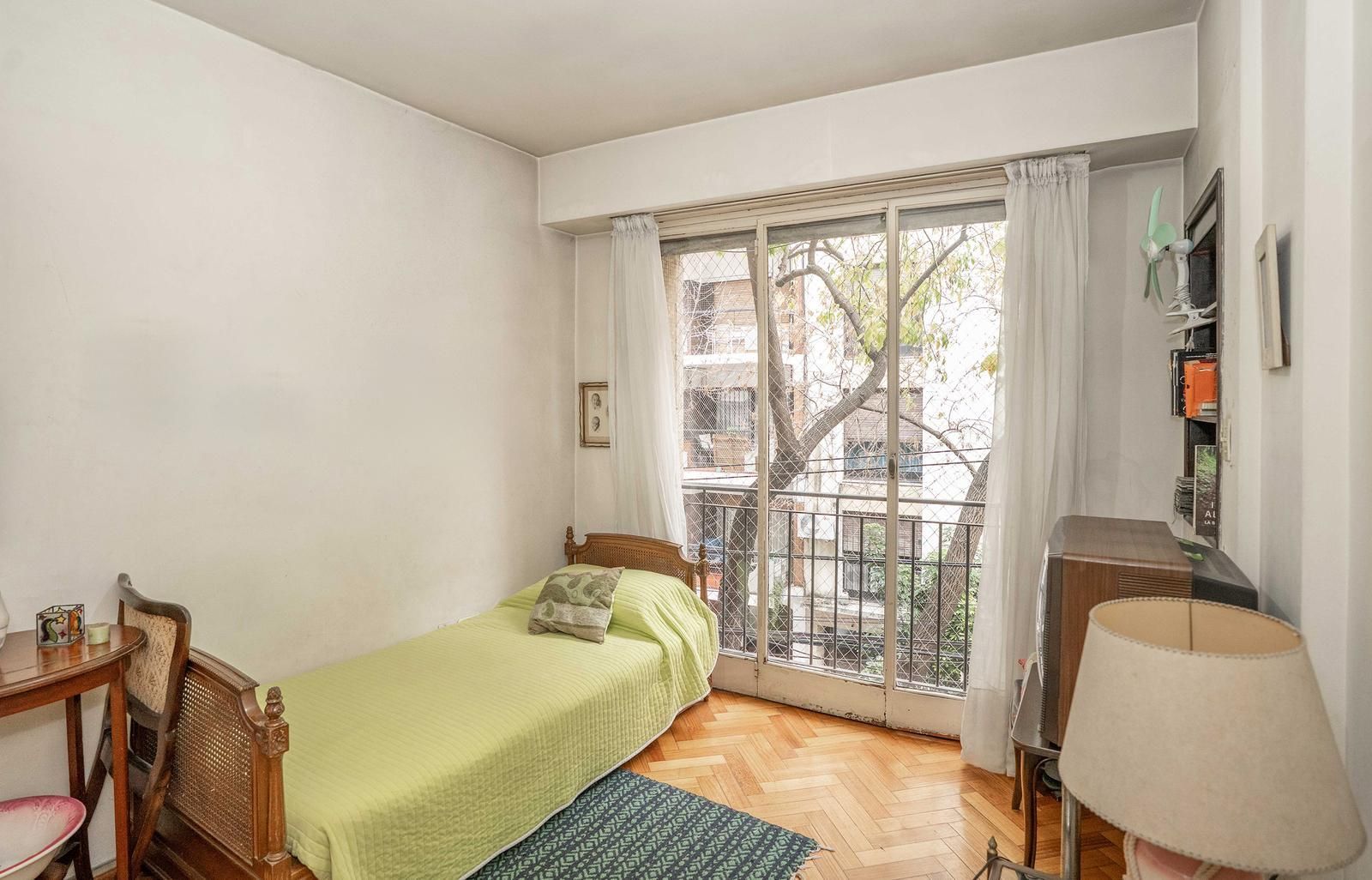 Edificio de apartamentos en una calle de la ciudad, con automóviles estacionados en el frente.