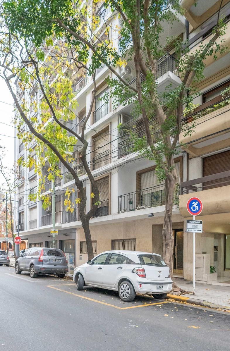 Edificio de apartamentos en una calle de la ciudad, con automóviles estacionados en el frente.