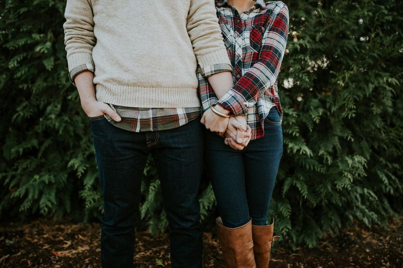 A man and a woman are holding hands in front of a tree.