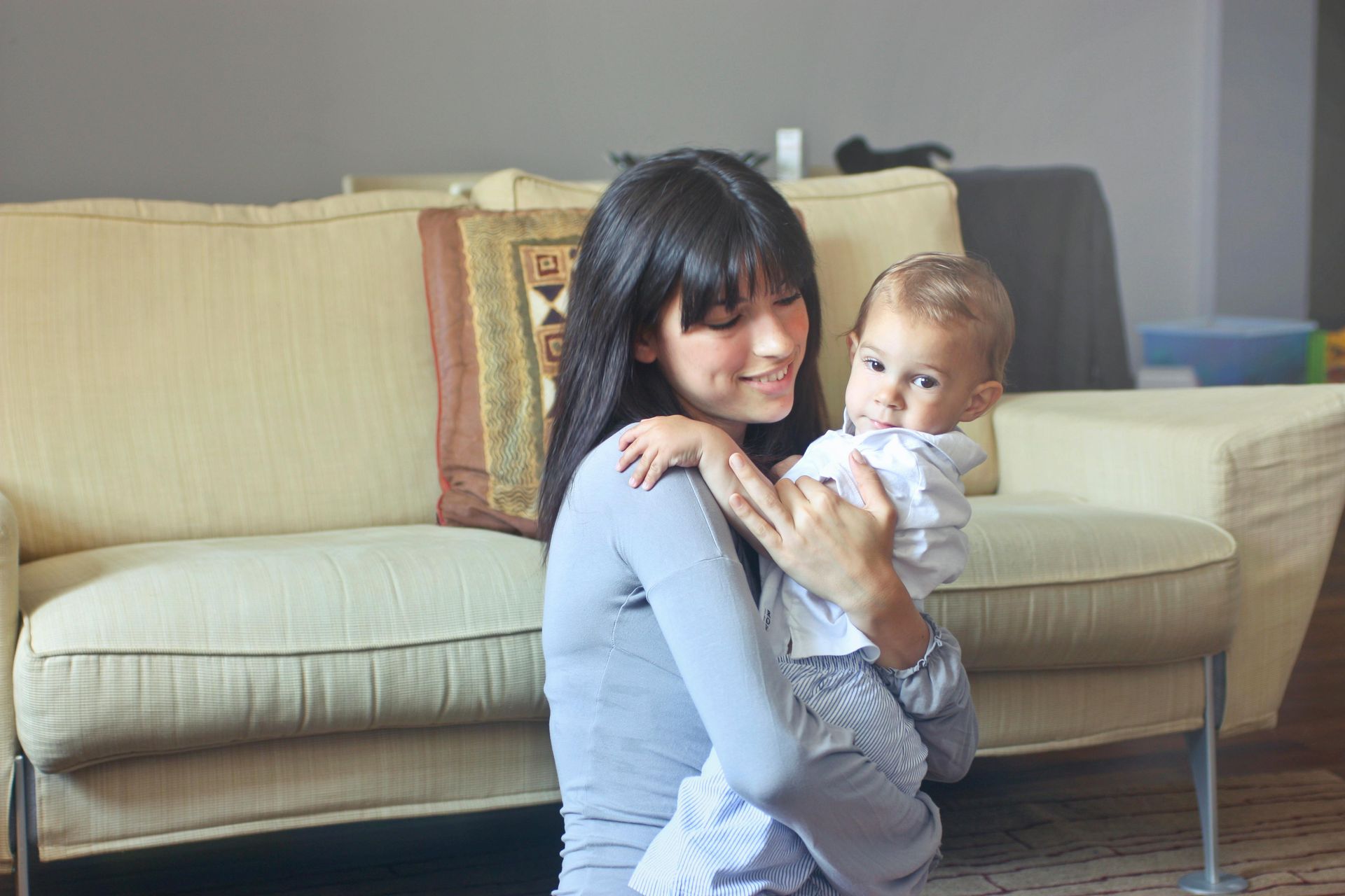 A woman is holding a baby in her arms in a living room.