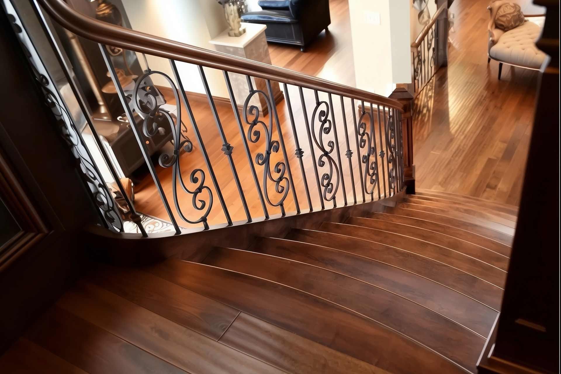 Wooden staircase with dark brown handrail and ornate black metal railing.