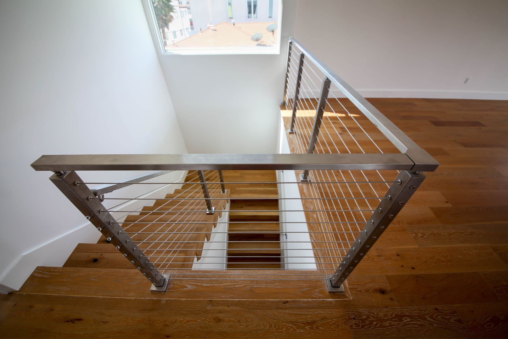 Staircase with wooden steps and modern stainless steel cable railing.