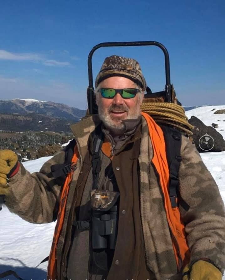 A man wearing sunglasses is standing in the snow